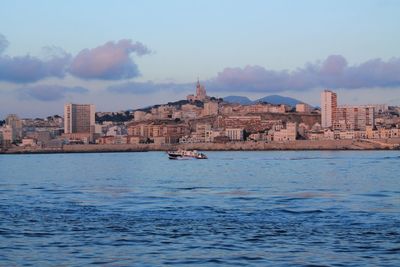 Buildings by sea against sky