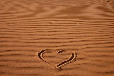 High angle view of heart shape on sand in desert