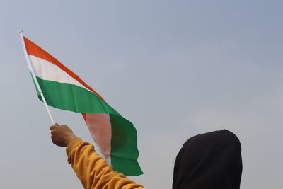 Low angle view of flag holding umbrella against sky