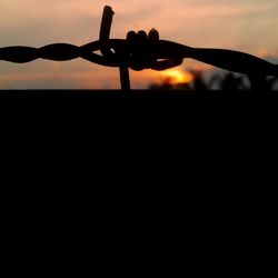 Close-up of silhouette metal against sky during sunset