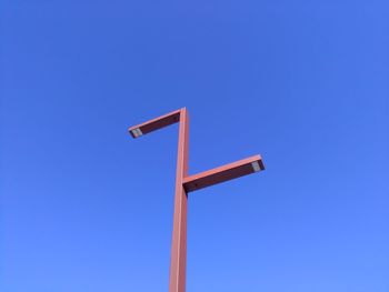Low angle view of metallic pole against clear blue sky