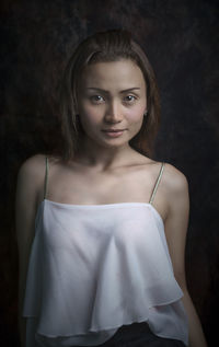 Portrait of young woman standing by wall