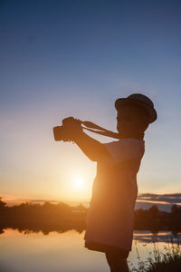 Side view of silhouette man standing against sky during sunset