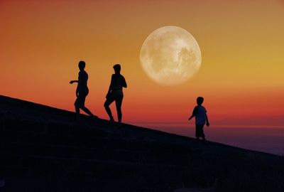 Silhouette of people walking up hill at sunset