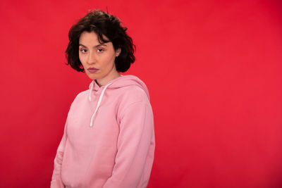 Portrait of woman standing against red background