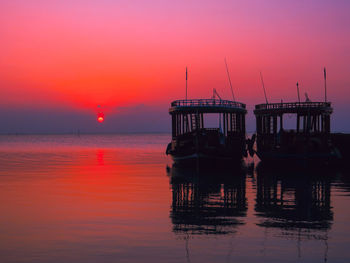 Silhouette of boats in sea against sky during sunset