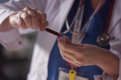 Midsection of doctor holding blood in syringe