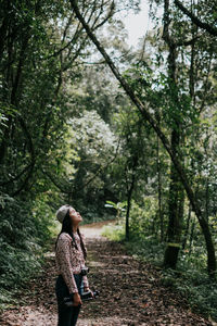 Side view of woman with eyes closed standing in forest