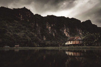 Scenic view of lake by trees and houses against sky