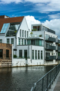 Buildings by river against sky