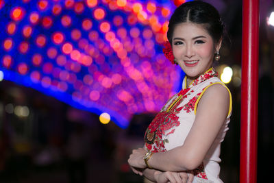 Portrait of smiling young woman standing at night