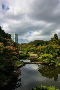 Scenic view of river amidst trees and buildings against sky