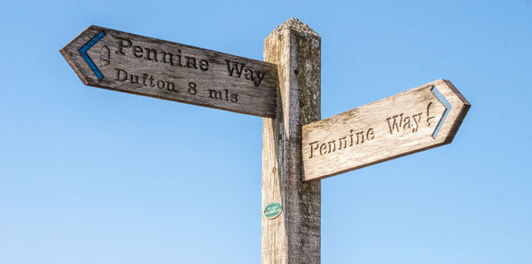 Low angle view of sign against blue sky