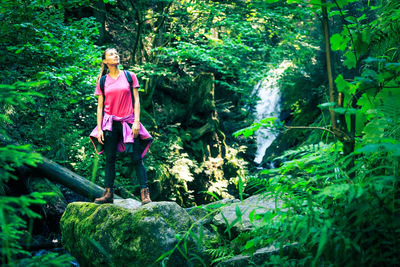 Woman standing amidst rocks in forest