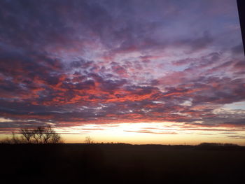 Scenic view of dramatic sky over silhouette landscape during sunset