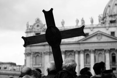 Close-up of people with cross against church