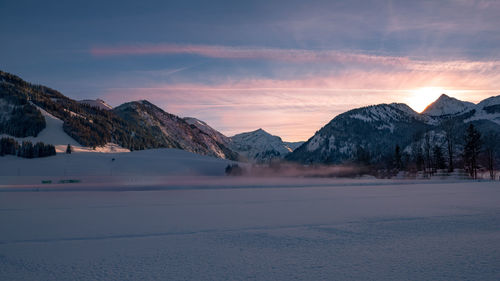 Scenic view of snow covered mountains against sky during sunset