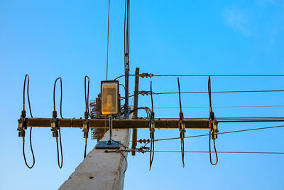 Low angle view of telephone pole against clear blue sky