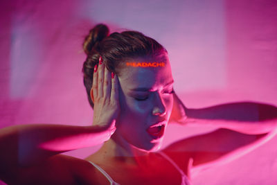 Portrait of beautiful young woman against pink background