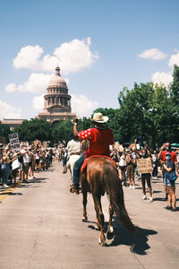 People riding horses on town square against sky