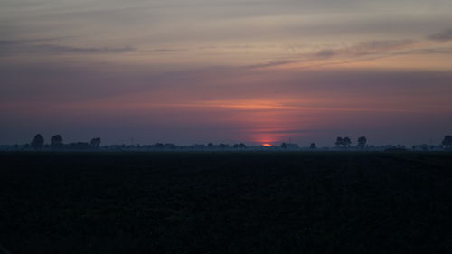 Scenic view of silhouette field against sky during sunset