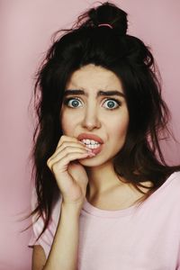 Portrait of woman making face against pink background