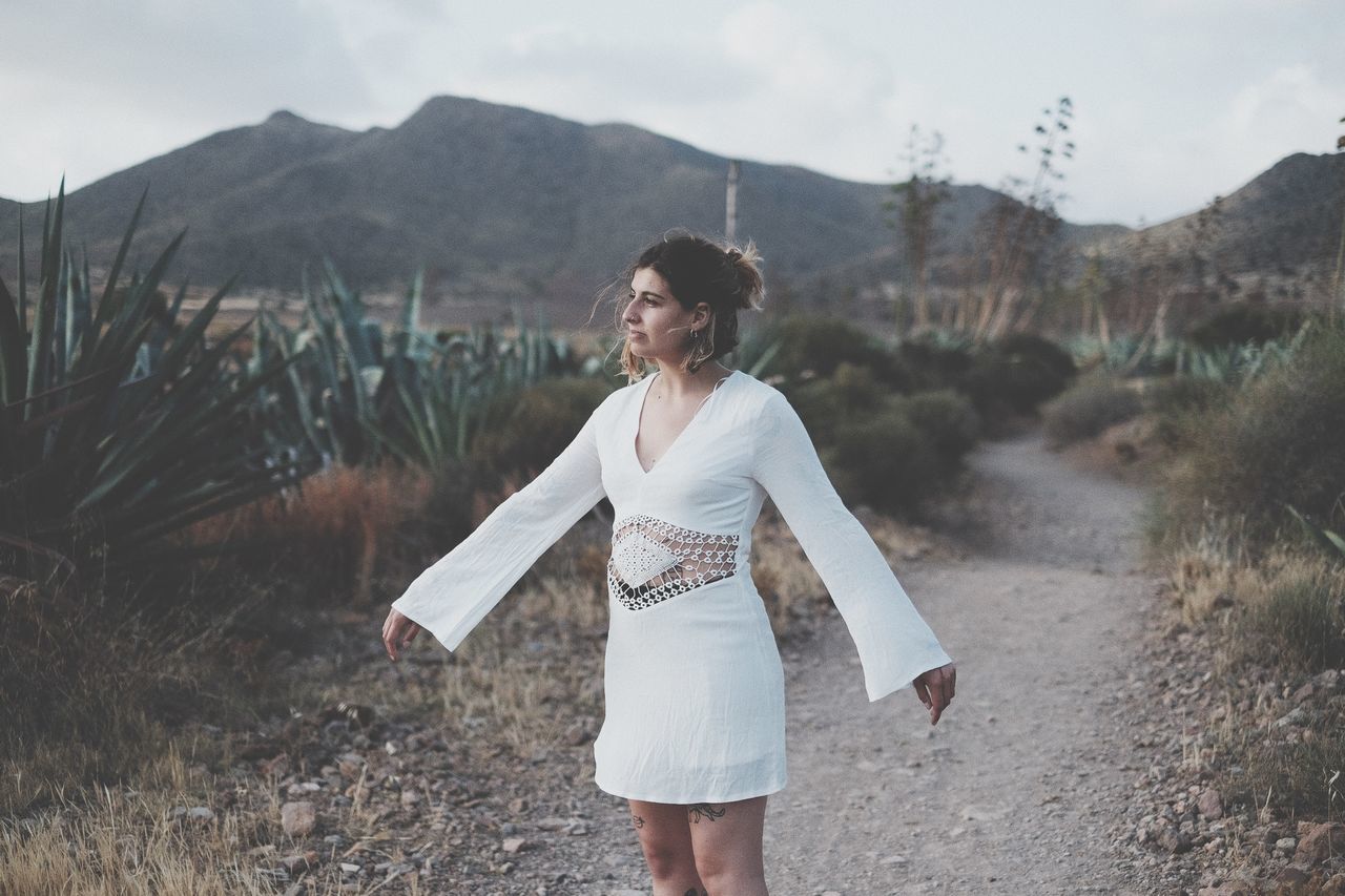 one person, mountain, real people, three quarter length, leisure activity, lifestyles, front view, nature, young adult, land, sky, standing, day, adult, casual clothing, scenics - nature, focus on foreground, women, outdoors, beautiful woman