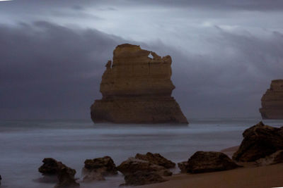 Rock formation on beach against sky