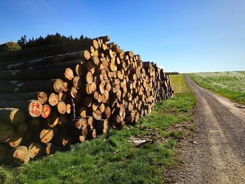 Stack of logs on field against clear sky