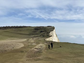 People walking on arid landscape against sky