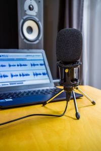 Close-up of microphone by laptop on table