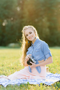 A beautiful young woman holds a retro camera in her hands. summer picnic person