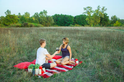 Full length of friends sitting on field