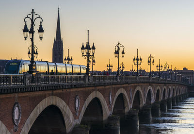 Bridge over river against sky during sunset