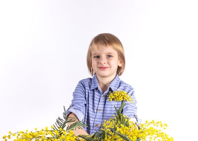 Portrait of smiling girl with yellow flower against white background
