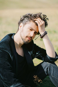 Man with hand in hair sitting outdoors