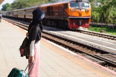 Rear view of man walking on railroad station