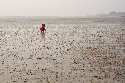 Girl playing at beach against sky