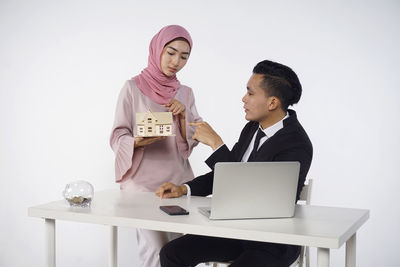 Man and woman using phone while sitting on table