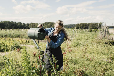 Female farmer watering plants in at farm