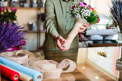 Midsection of florist holding bouquet at table in flower shop