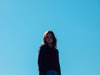 Portrait of woman standing against clear blue sky