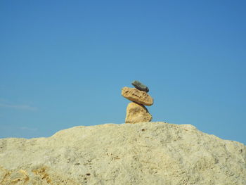 Stacked stones at beach against clear blue sky