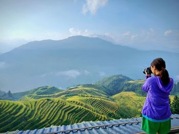 Rear view of young woman photographing terraced field