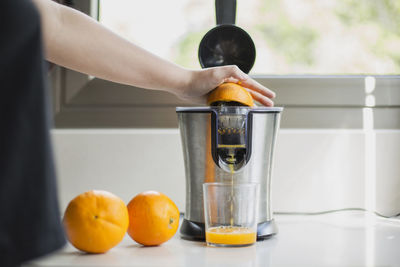 Close-up of hand holding orange juice on table