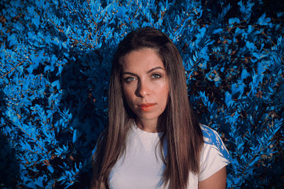 Portrait of beautiful young woman against plants