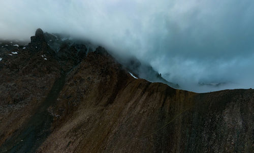 A mountain range in the clouds above the top. mountains. mount alakel north. travel in kyrgyzstan.