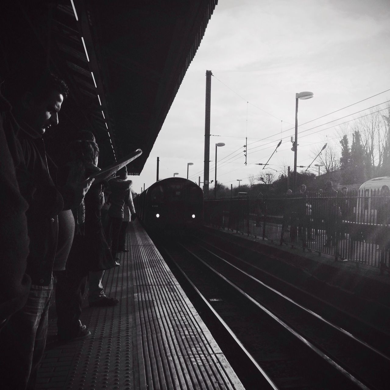 railroad track, transportation, sky, the way forward, rail transportation, diminishing perspective, built structure, railing, vanishing point, railroad station platform, cloud - sky, metal, architecture, railroad station, mode of transport, outdoors, dusk, public transportation, street light, day