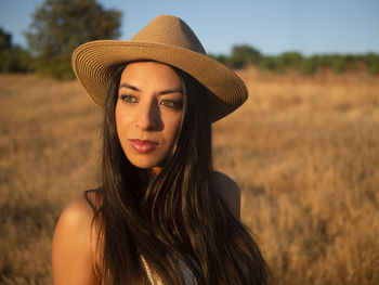 Portrait of young woman wearing hat standing on field