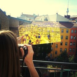 Cropped image of woman photographing through smart phone in city